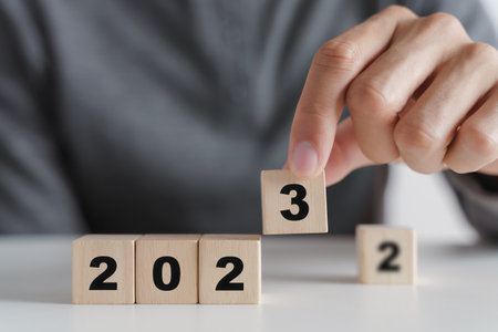 Man hand putting wooden cube block to change 2022 year to 2023 year. start to year 2023. happy new...