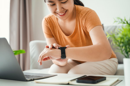 young woman looking and using a smartwatch, Female sitting on the sofa checking her smartwatch.の写真素材