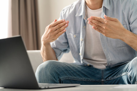 Young deaf man using laptop computer for online video conference call learning and communicating in...