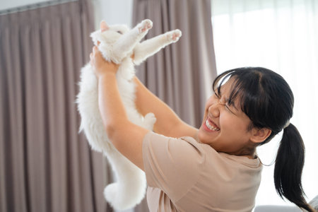 Happy Woman Playing with Cat in Cozy Living Room at Home.の写真素材