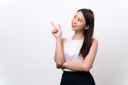 A woman is pointing to the sky with her finger. She is wearing a white shirt and black skirtの写真素材