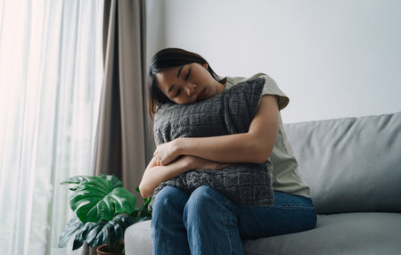 Unhappy lonely depressed woman is sitting on the couch. She looks sad and tired.の写真素材