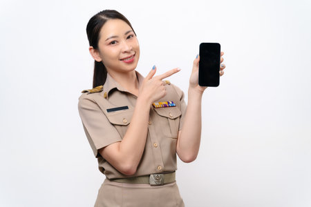 A beautiful Thai Asian Teacher in the uniform shows a blank screen of mobile phone. She smiles at...