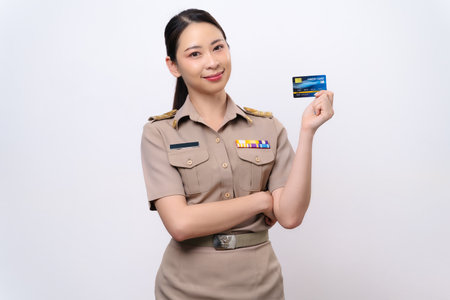 Young Thai Asian Teacher in the uniform is holding the credit card and look at the camera isolated on white background.の写真素材