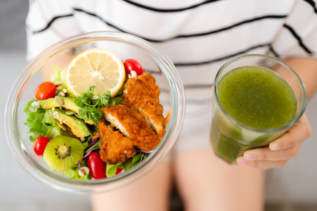Beautiful Asian woman holding a bowl of salad and green vegetable and fruit juice. Healthy food concept.の写真素材