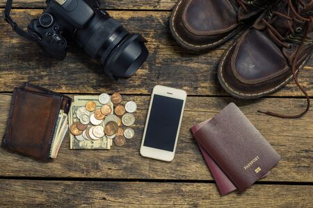 holiday concept, Preparation for travel,smartphone money and passport with camera on wooden tableの写真素材
