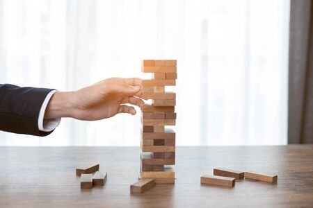Businessman hands play wood block tower game.の写真素材