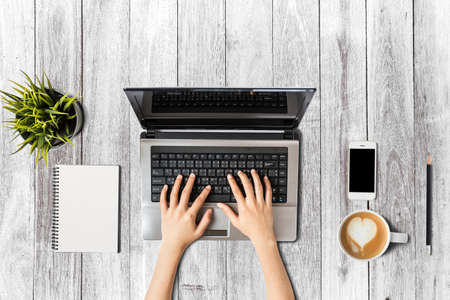 Top View of Businesswoman Working on a wooden office desk with Computer and office Supplies