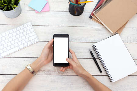 hand woman using a telephone, empty screen smart phone and computer on wooden table In home office.