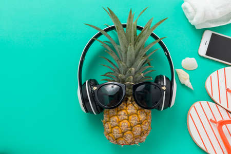 Summer Holidays background Concept, Phone with pineapple, glasses and flip flops On a green and...