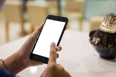 hand woman using a telephone, empty screen smart phone and computer on wooden table .の写真素材