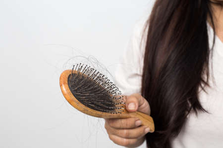 young woman worried about hair loss on a white backgroundの写真素材