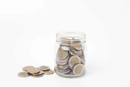 Coins  in a glass jar on a white backgroundの写真素材