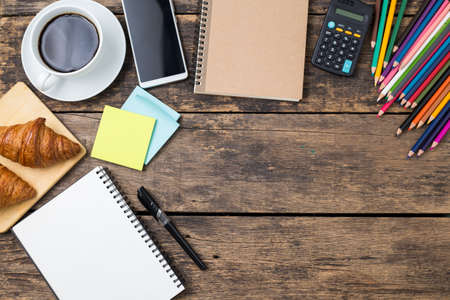 Top view, empty notebook and office supplies on old wooden table.