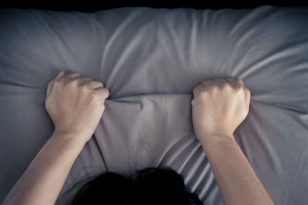 Female hand pulling brown sheets. ,sign orgasm of woman on  bedの写真素材