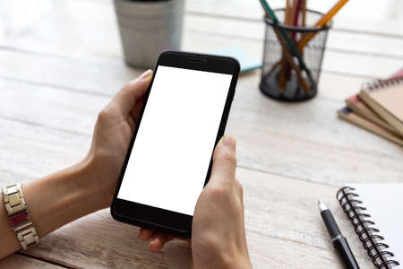 hand woman using a telephone, empty screen smart phone and computer on wooden table In home office.