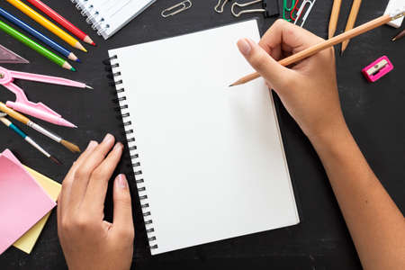 Girl hand drawing, blank paper with colorful pencils and School Supplies on  wooden tableの写真素材