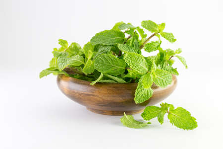 mint leaf in a wooden bowl isolated on white backgroundの写真素材