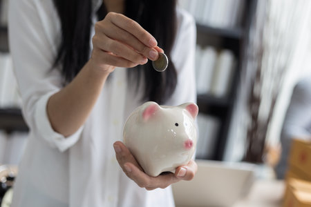Portrait of smiling asian young woman hold piggy bank and Coin , savings and banking conceptの写真素材