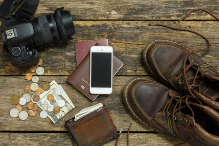 holiday concept, Preparation for travel,smartphone money and passport with camera on wooden tableの写真素材