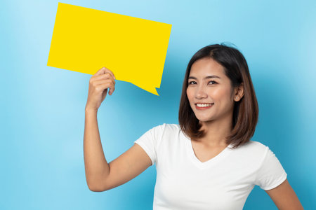 Portrait of young girl holding a empty yellow speech bubble isolated on blue background