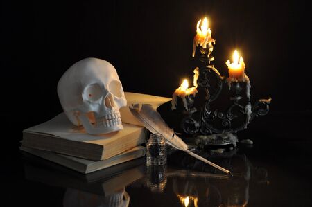 Still life with scull, books and candles on black backgroundの写真素材