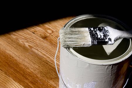 Paint Bucket on Hardwood Floor with Paintbrushの写真素材