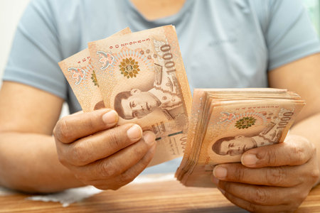 Asian woman counting Thai baht banknote money, investment economy, accounting business and banking.
