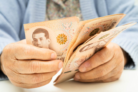 Asian elder senior woman patient holding Thai banknotes money in her hand, Cost of living and...