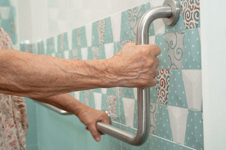 Asian elderly woman patient use handrail safety in toilet support rail in bathroom.の写真素材