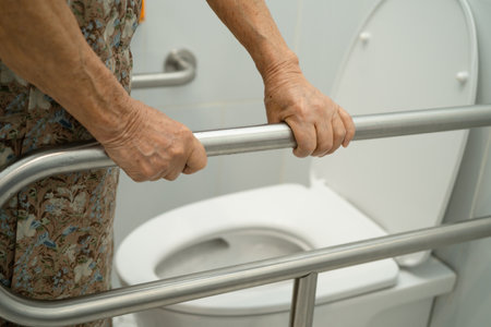 Asian elderly woman patient use toilet support rail in bathroom.の写真素材