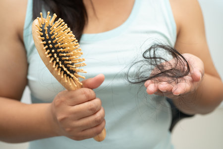 Asian woman have problem with long hair loss attach to comb brush.の写真素材