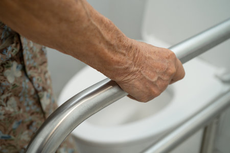 Asian elderly woman patient use toilet support rail in bathroom.の写真素材