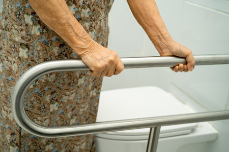 Asian elderly woman patient use toilet support rail in bathroom.の写真素材