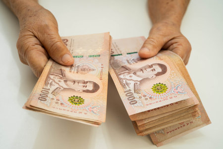 Asian elder senior woman patient holding Thai banknotes money in her hand, Cost of living and medical care.の写真素材