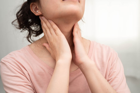 Asian woman touching her neck and throat for thyroid gland problem.の写真素材