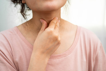 Asian woman touching her neck and throat for thyroid gland problem.の写真素材