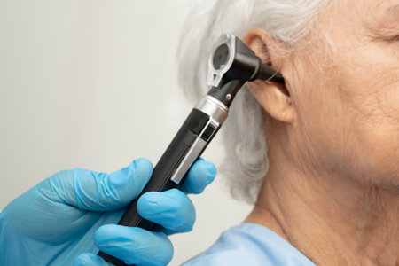 Otolaryngologist or ENT physician doctor examining senior patient ear with otoscope, hearing loss...