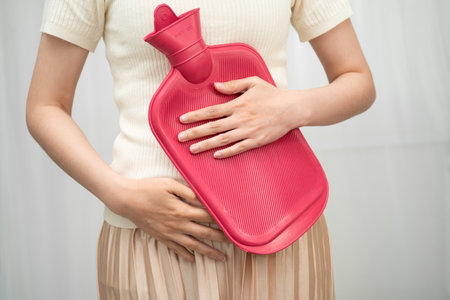 Woman using hot water bottle to relieve menstrual abdominal pain.の写真素材