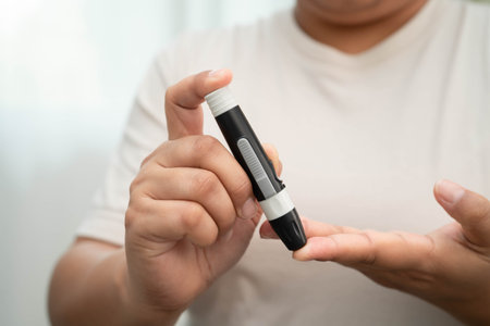 Asian woman self testing to check blood sugar level diabetes by digital lancet on finger at home.