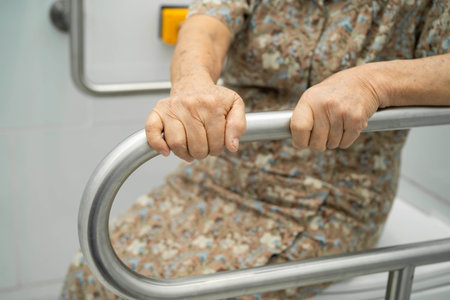 Asian elderly woman patient use toilet support rail in bathroom.の写真素材