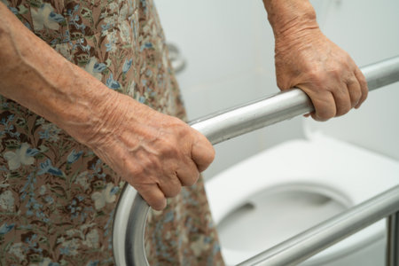 Asian elderly woman patient use toilet support rail in bathroom.の写真素材