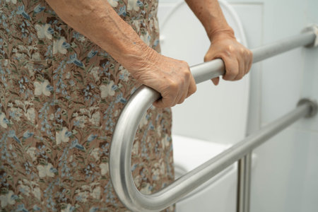 Asian elderly woman patient use toilet support rail in bathroom.の写真素材
