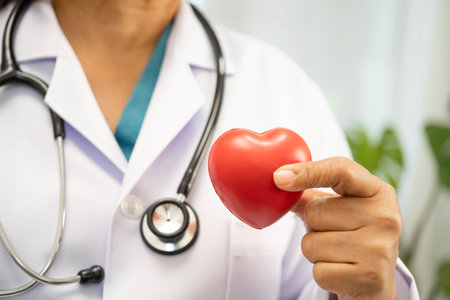 Asian woman doctor holding red heart for health in hospital.の写真素材