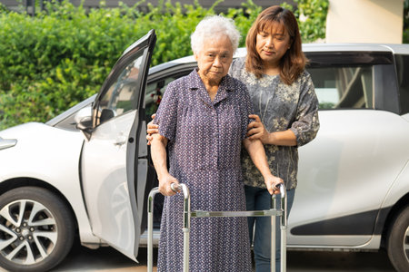 Caregiver help Asian elderly woman disability patient get in her car.
