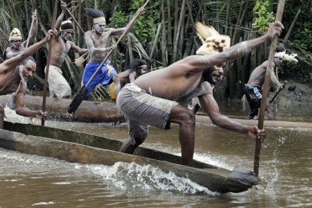 INDONESIA, NEW GUINEA, ASMAT PROVINCE, JOW VILLAGE - JUNY 28: The Asmat Warriors  with a spear - oars float on the dugout canoes, national dresses, neckless, the weapons, painting. New Guinea, Indonesia. June 28 2012のeditorial素材