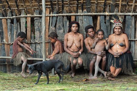 DUGUM DANI VILLAGE, BALIEM VALLEY, IRIAN JAYA, NEW GUINEA, INDONESIA - JUNE 20: Women and children of a new Guinean tribe Dugum Dany in traditional the village at the hovels. Traditional clothes and Painting. June 20, 2012, Baliem Valley, Irian Jaya, Indoのeditorial素材