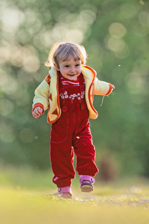 Happy baby girl running at green field  Active little girl running on a meadow の写真素材