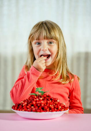 Happy little girl with wild strawberries,の写真素材