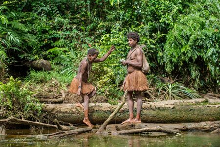 WILD JUNGLE, IRIAN JAYA, NEW GUINEA, INDONESIA - JUNE 09, 2016: Fishing  Papuan woman of the Korovai tribe on the river in the jungle of New Guinea Island. Irian Jaya, Indonesia. June 09, 2016のeditorial素材